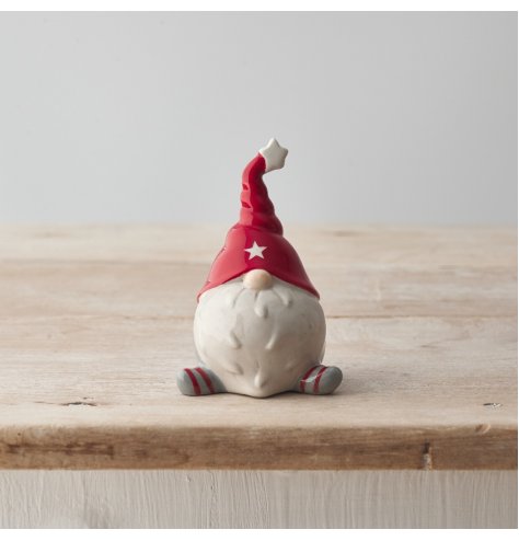 A charming ceramic gonk ornament in a seated position with stripe legs and a star design twisted hat. 