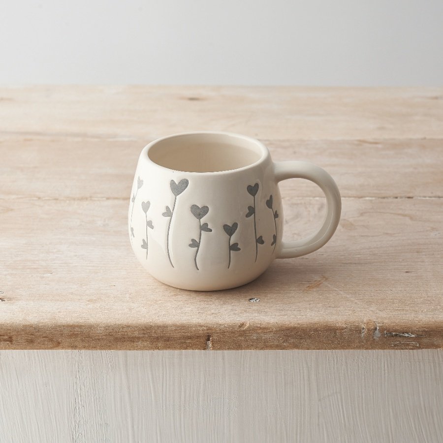 A stylish ceramic mug featuring a sweet heart shaped floral stem design in grey. 