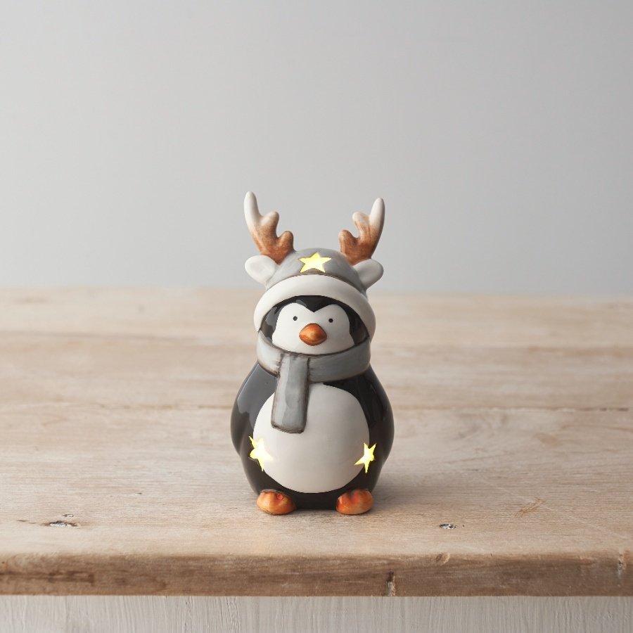 An adorable ceramic penguin ornament with warm glow led lights and star cut out details. 