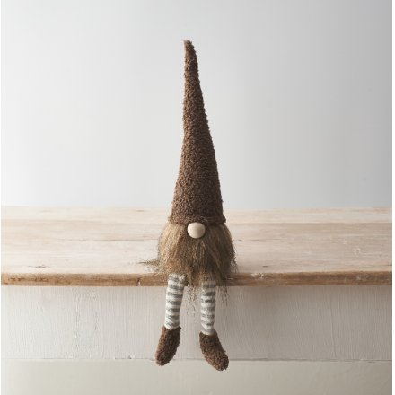 A cute gonk decoration with stylish sherpa fabric hat and shoe details with dangly striped legs in neutral brown tones.