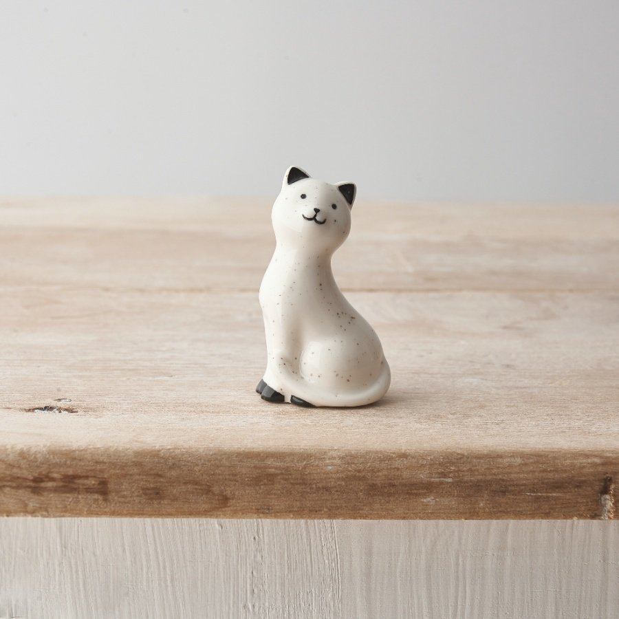 A small porcelain decoration with cat design featuring a cute face and speckled design. 