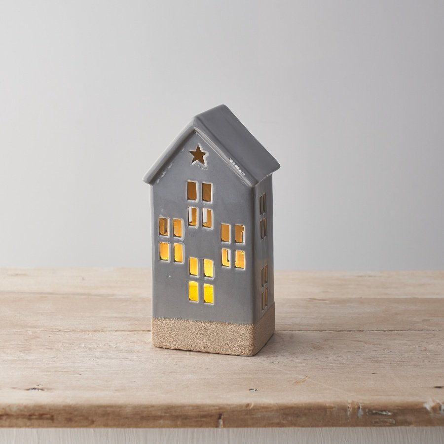 A house shaped ceramic decoration with cut out design. light up features and star detail. 