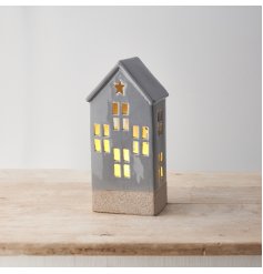 A ceramic house decoration with light up feature, cut out design and star detail. 