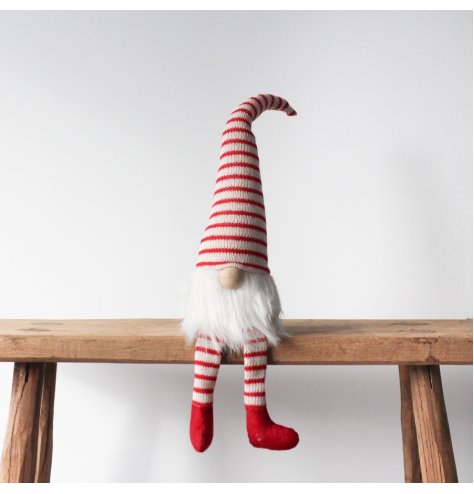 A colourful and festive candy cane design knitted gonk with a long white beard and wooden nose.