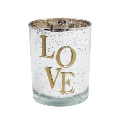 A glass tea light holder with "love" text and a distressed effect gold metallic finish.