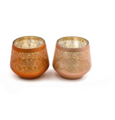 A glass tea light holder with an intricate metallic pattern in a stylish burnt orange colour. 