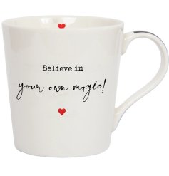 A classic white ceramic mug with "believe in your own magic" message and dainty red heart details. 