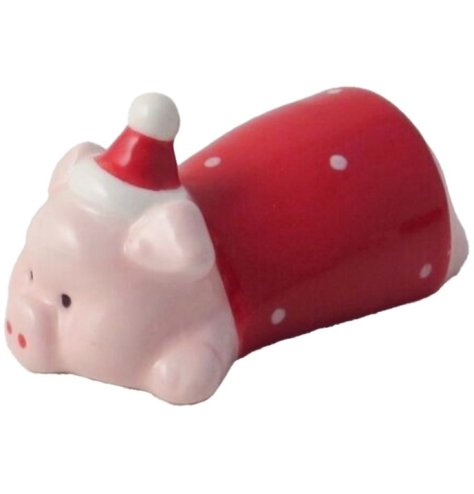 A laying Christmas pig figure wrapped in a traditional red blanket, wearing a Santa hat.