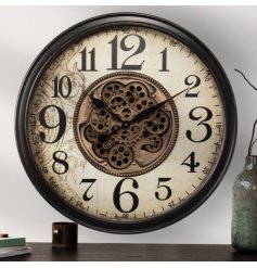 A large wall clock with central cog mechanism design, black edging, clock hands and numbers with a beautiful background.