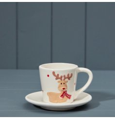 a ceramic cup and saucer set displaying a reindeer wearing a red scarf