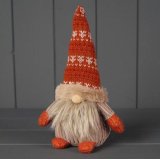 A rustic looking gonk in a festive patterned hat with a wooden nose.
