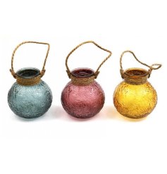 An assortment of 3 colourful glass lanterns in earthy blue, pink and yellow colours. 