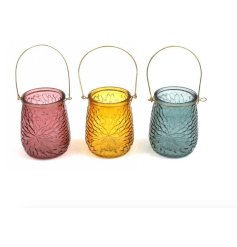 An assortment of  3 colourful glass lanterns in pink, yellow and blue designs.