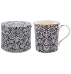 A ceramic mug with William Morris 'Sunflower' pattern and gold rim detail, presented in a matching tin. 