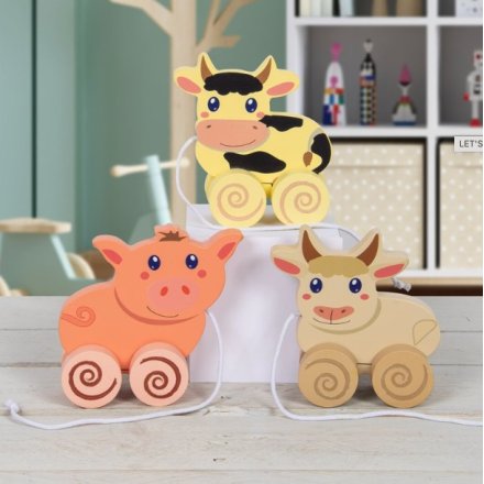 Traditional wooden pull along toys in the form of three assorted farm animals. A cow, pig and highland cow.