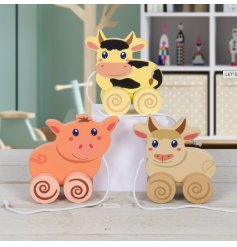 Traditional wooden pull along toys in the form of three assorted farm animals. A cow, pig and highland cow.
