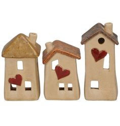 An assortment of 3 charming houses with heart details and a reactive glaze finish. 