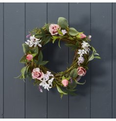 A floral wreath featuring colourful artificial flowers including pink roses. 