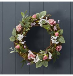 A pretty floral wreath featuring pastel coloured artificial flowers including roses. 