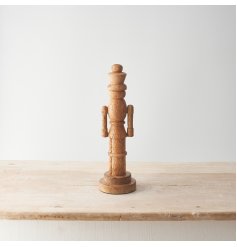 A contemporary nutcracker decoration carved from natural mango wood. With a smooth finish and visible wood grain. 