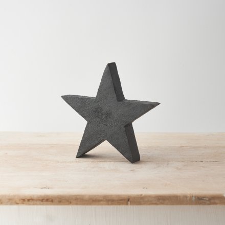 A contemporary Christmas star decoration made from natural mango wood and painted with a bold black wash. 