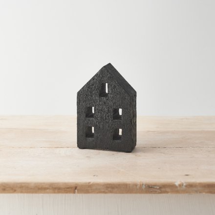 A contemporary carved wooden house with a black painted finish. 