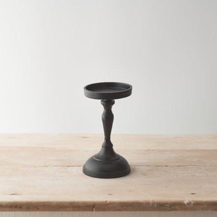 A minimalist black pillar candle holder made from metal. A stylish interior accessory for the home. 
