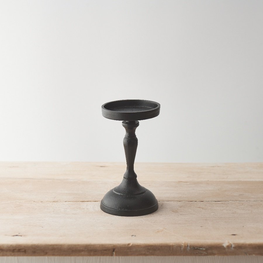 A black metal candle holder for displaying pillar candles. An elegant interior accessory to compliment many interiors