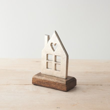 A stylish interior accessory featuring a silver metal house with windows and heart detail set proudly upon a mango base