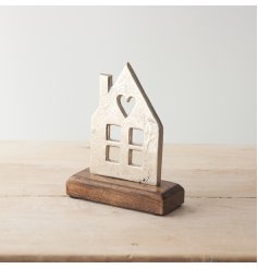 A silver metallic house decoration on a chunky wooden base. A chic item with cut out features and heart motif. 