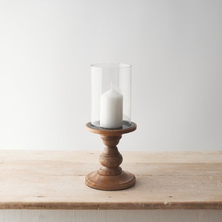 Pillar candle holder made from glass on a wooden stand