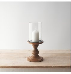 Pillar candle holder made from glass on a wooden stand