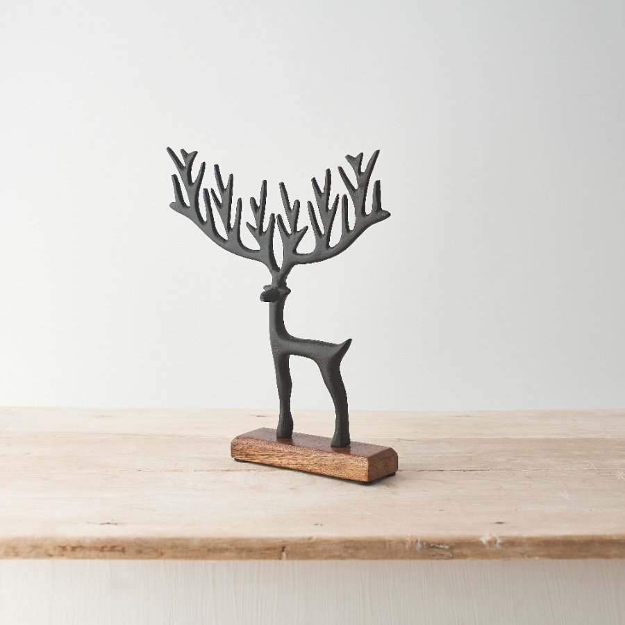 A chic decorative item featuring a black painted reindeer design with exaggerated antlers on a wooden base. 