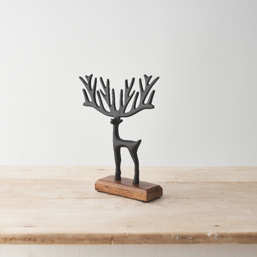 A stylish reindeer decoration featuring a sculptural black finish reindeer on a contrasting wooden base. 