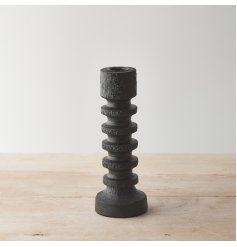A wooden pillar candle with a stylish black finish and minimalist sculptural design