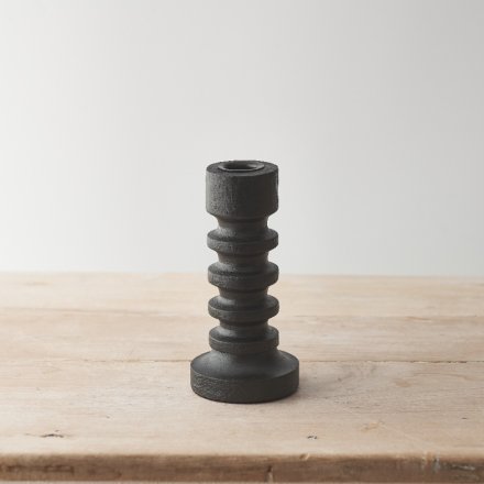 A wooden pillar candle with a stylish black finish and minimalist sculptural design. 