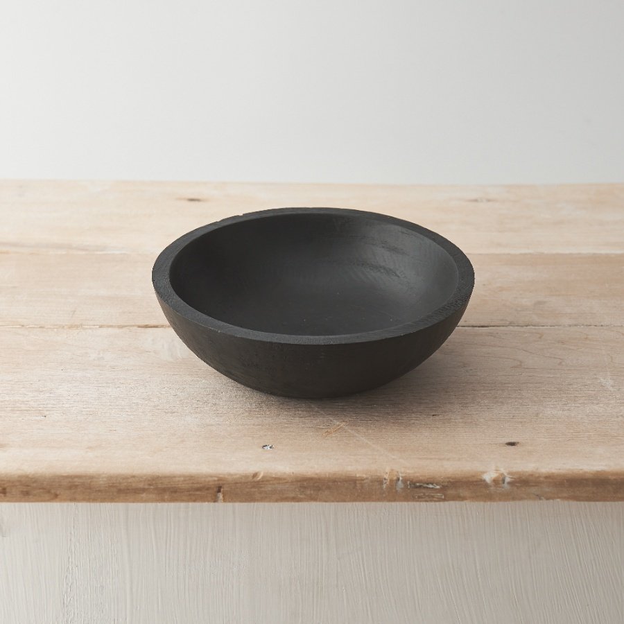 A beautifully crafted chunky wooden bowl with a rustic black finish. 