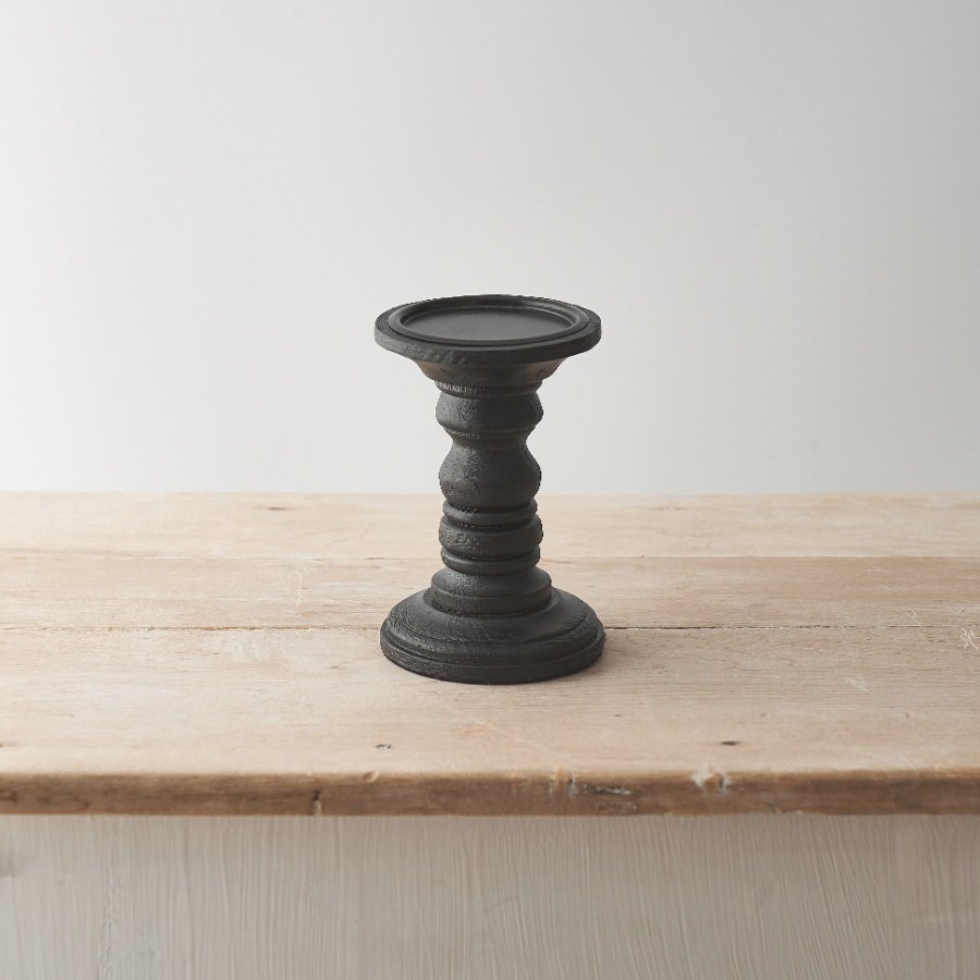 This wooden candle stand has a black painted finish with a simple yet sculptural design.