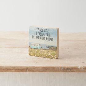 A decorative wooden block with camper van print and "it's not about the destination, it's about the journey" text. 