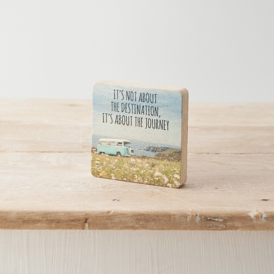 A decorative wooden block with camper van print and "it's not about the destination, it's about the journey" text. 