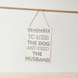 A cheeky sign with "remember to kiss the dog and feed the husband" text on a distressed background with rope hanger. 