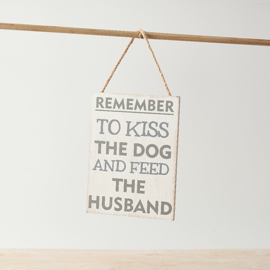 A humorous sign with distressed background and "remember to kiss the dog and feed the husband" text.