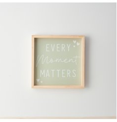 A stylish framed wooden sign featuring "every moment matters" quote on a sage green background with heart details. 