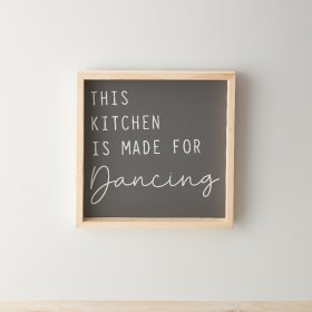A stylish wooden framed sign with "this kitchen is made for dancing" quote on a dark background. 