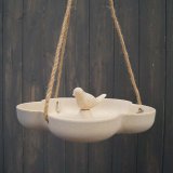 A natural bird bath / feeder hanging from twine with a simple bird sitting in the centre