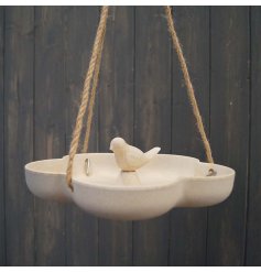 A natural bird bath / feeder hanging from twine with a simple bird sitting in the centre