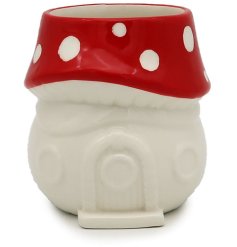 A whimsical and unique fairy house oil burner with a red and white polka dot toadstool roof.