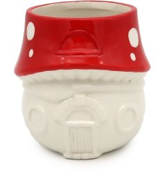 An enchanting ceramic planter with a fairy house and glazed toadstool design. 