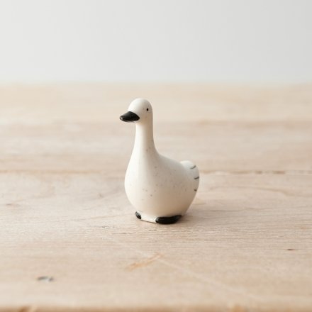 A small porcelain duck ornament in black and white with a smooth, speckled finish. 