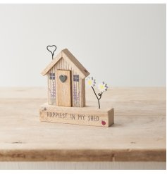 A rustic wooden decoration with shed design and "happiest in my shed" text, with floral details and wire embellishments.